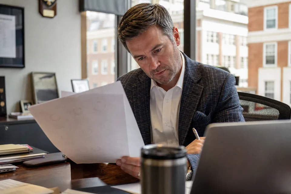 Contracts director at a defense electronics firm reviewing a subscription quote with a pen