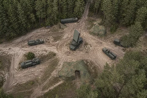 Aerial view of an air defence battery site with radar and launcher vehicles on a forest clearing