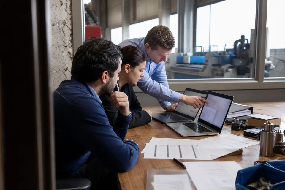 Business development team at a defense supplier comparing tender lists on two laptops
